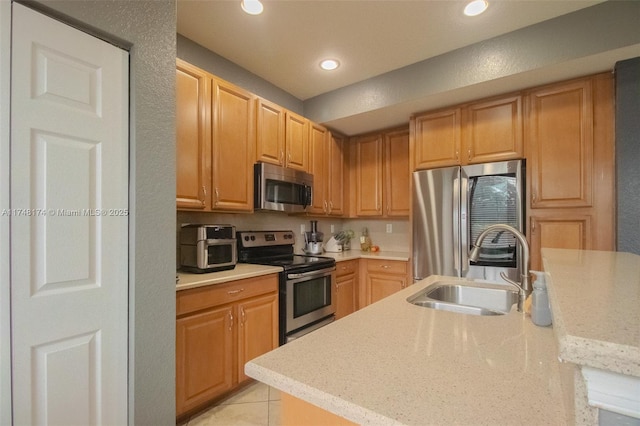 kitchen with light tile patterned floors, appliances with stainless steel finishes, light stone countertops, a sink, and recessed lighting