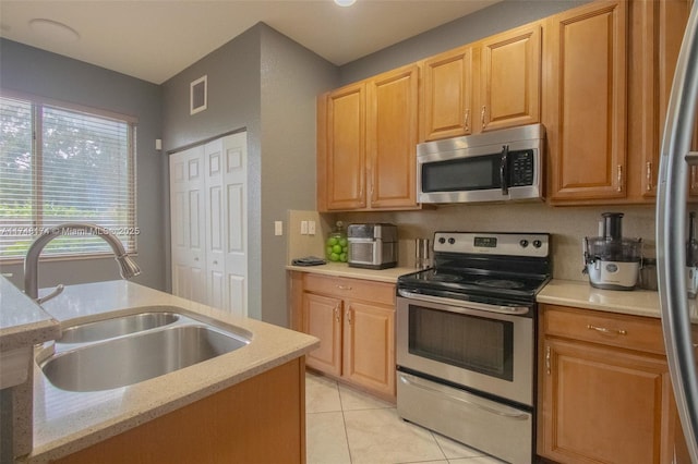 kitchen featuring light tile patterned floors, stainless steel appliances, visible vents, a sink, and light stone countertops