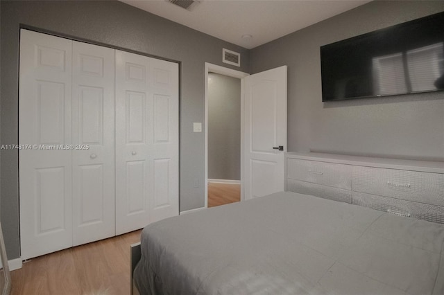 bedroom with a closet, visible vents, and light wood-style flooring