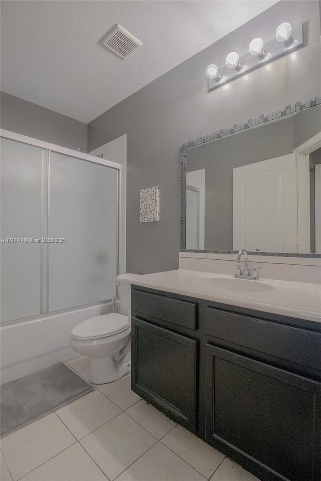 bathroom featuring tile patterned flooring, toilet, bath / shower combo with glass door, vanity, and visible vents