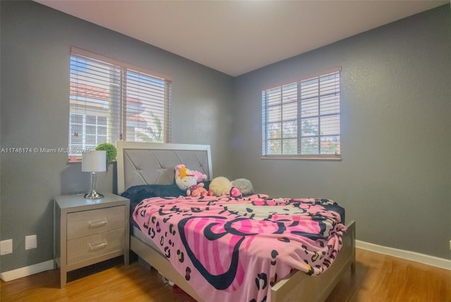 bedroom featuring baseboards, multiple windows, and light wood finished floors