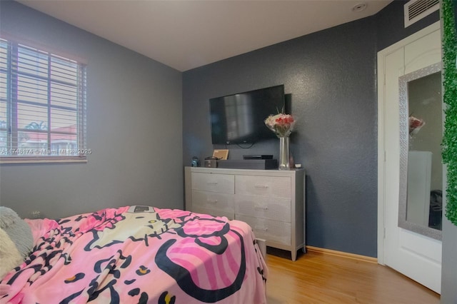 bedroom with light wood-style floors, visible vents, and baseboards