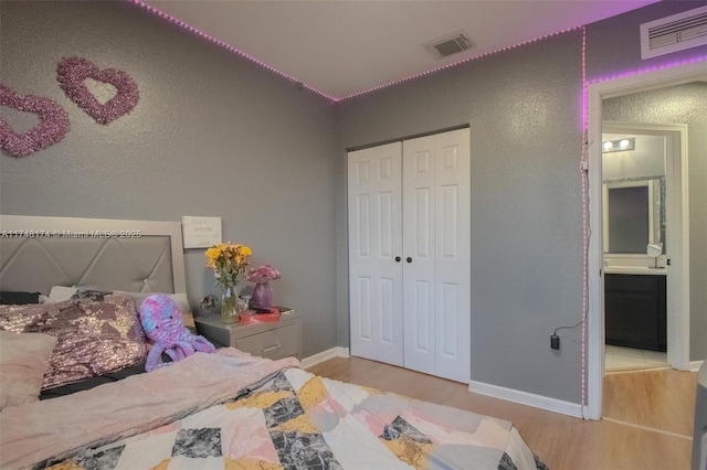 bedroom featuring light wood-style flooring, a closet, visible vents, and baseboards