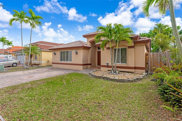 view of front of house with decorative driveway, fence, a front lawn, and stucco siding