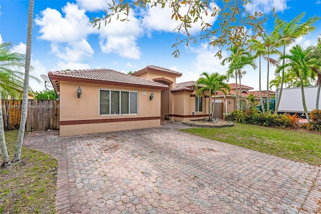 view of front of home featuring fence, a tile roof, and stucco siding