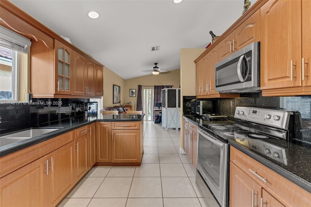 kitchen featuring light tile patterned floors, lofted ceiling, glass insert cabinets, a peninsula, and stainless steel appliances