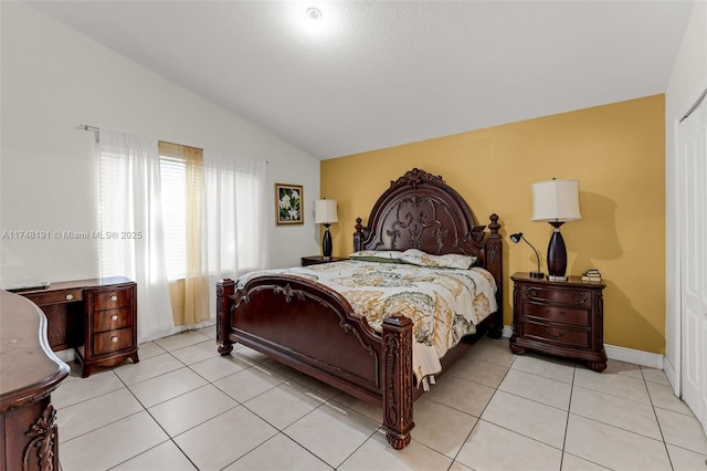 bedroom with lofted ceiling, light tile patterned flooring, and baseboards