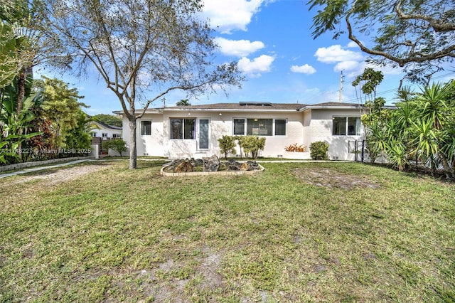 ranch-style home with a front yard and roof mounted solar panels