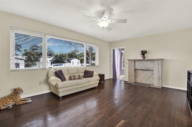 living area with a fireplace, wood finished floors, a ceiling fan, and baseboards