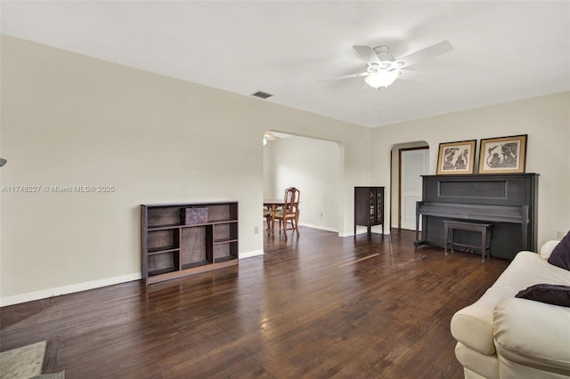 living room with wood finished floors, visible vents, a ceiling fan, arched walkways, and baseboards