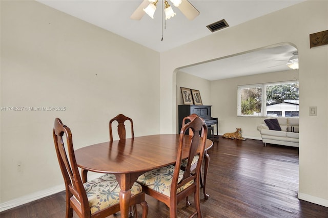 dining space featuring wood finished floors, ceiling fan, arched walkways, baseboards, and visible vents