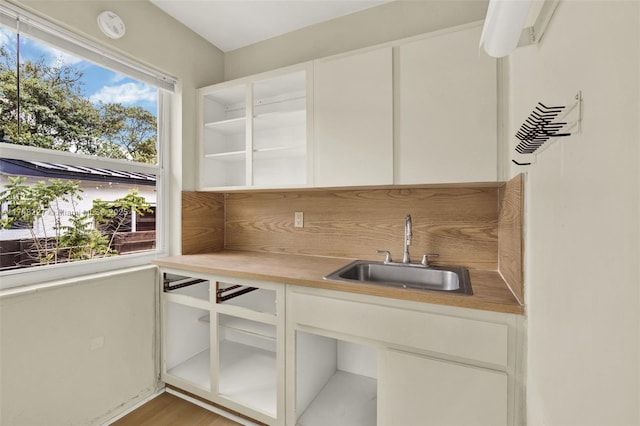 bar with indoor wet bar, a sink, and light wood-style flooring