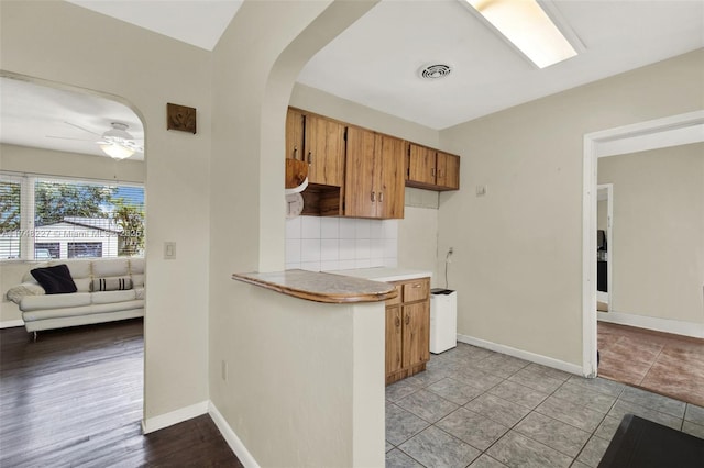 kitchen featuring brown cabinets, light countertops, visible vents, tasteful backsplash, and ceiling fan