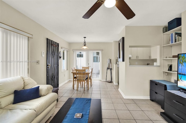 living room featuring baseboards, ceiling fan, and light tile patterned floors