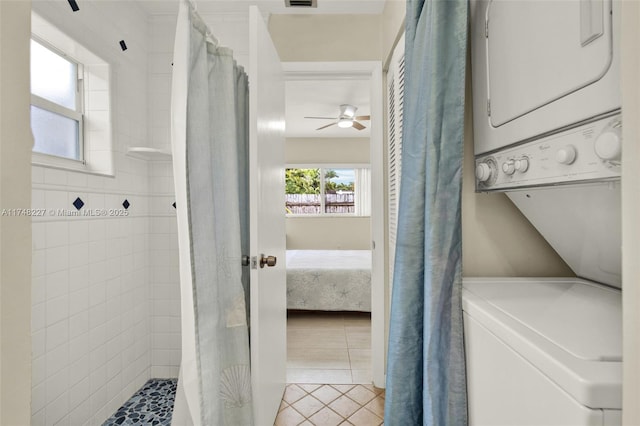 washroom with a ceiling fan, stacked washer / dryer, light tile patterned floors, laundry area, and visible vents