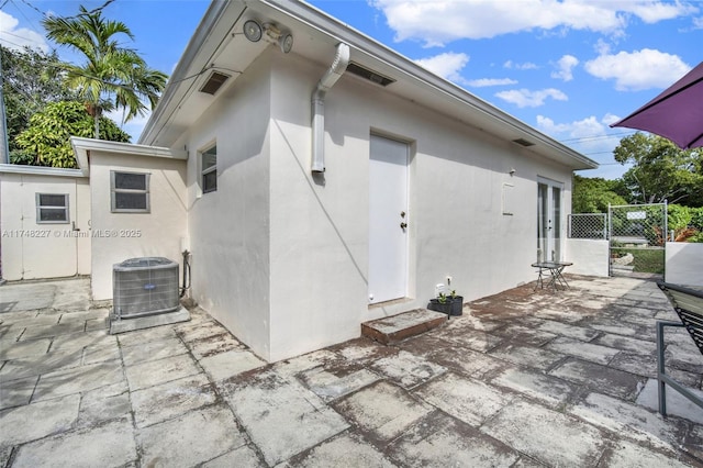back of property featuring stucco siding, a patio, central AC unit, and fence