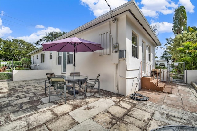 view of patio with a gate, outdoor dining space, and fence