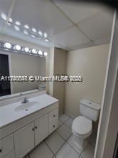 bathroom with toilet, a paneled ceiling, tile patterned flooring, and vanity