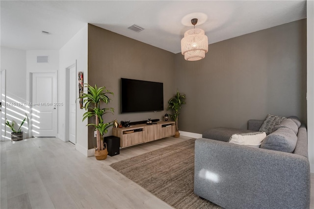 living room with light wood-type flooring, baseboards, and visible vents