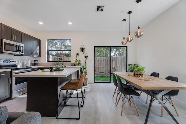 kitchen featuring visible vents, a kitchen island, appliances with stainless steel finishes, a breakfast bar area, and light countertops