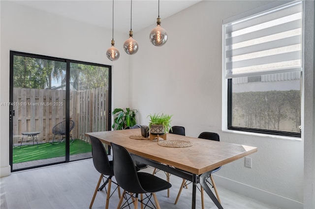 dining space with light wood-type flooring and baseboards