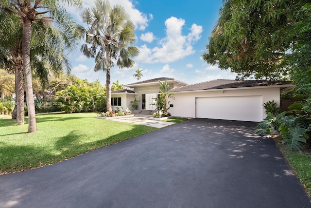 prairie-style home with a garage, aphalt driveway, a front lawn, and stucco siding