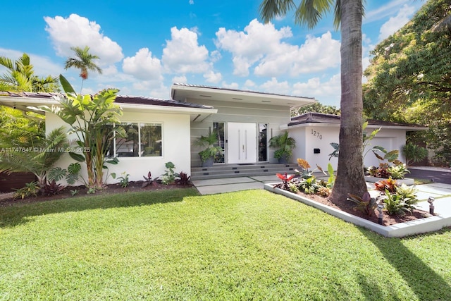 view of front of house featuring stucco siding, a front yard, and a garage