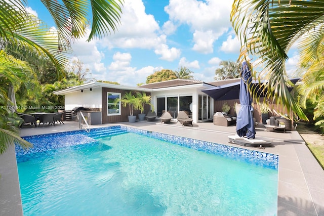 pool with area for grilling, outdoor lounge area, and a patio area