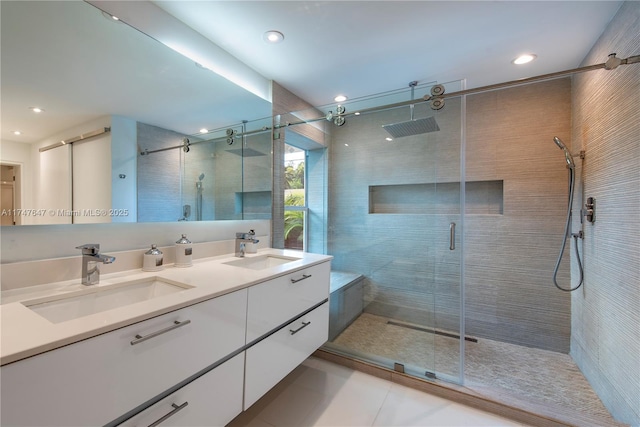 bathroom featuring double vanity, a stall shower, a sink, and tile patterned floors