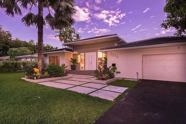 view of front of property with a garage, a yard, and stucco siding