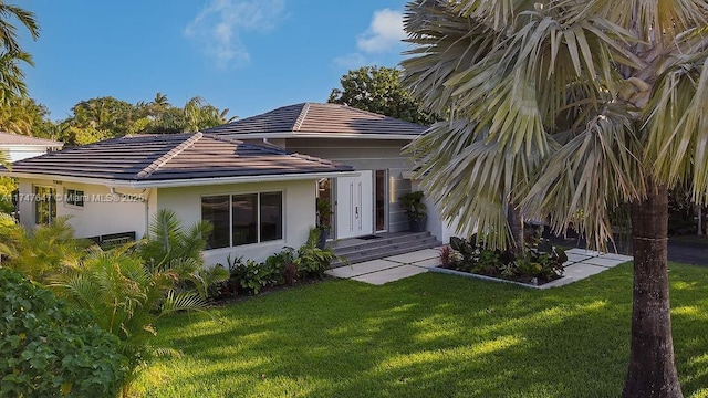 view of front of home featuring a tiled roof, a front lawn, and stucco siding