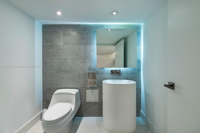 bathroom featuring recessed lighting, toilet, and tile walls