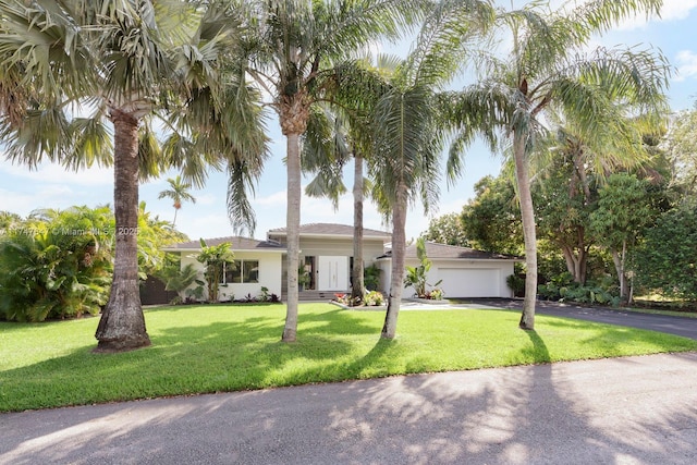 view of front of house with aphalt driveway, a front lawn, and an attached garage