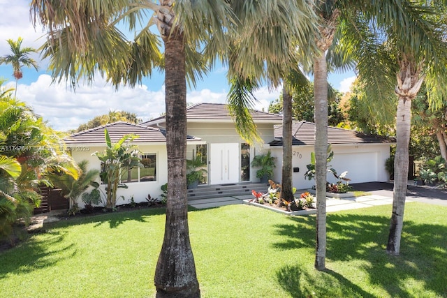 view of front facade featuring stucco siding, an attached garage, a front yard, and a tile roof
