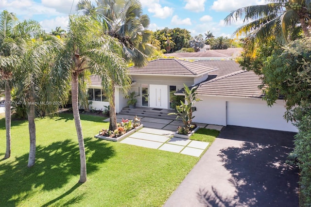 view of front of home featuring a front lawn, driveway, french doors, an attached garage, and a tiled roof
