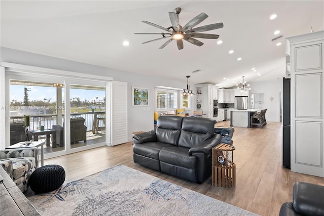 living area with recessed lighting, visible vents, lofted ceiling, light wood-style floors, and ceiling fan with notable chandelier