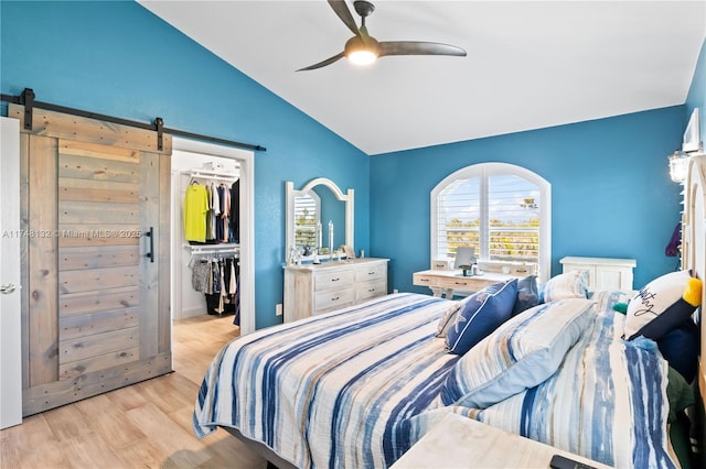 bedroom with lofted ceiling, a barn door, a spacious closet, a closet, and light wood finished floors