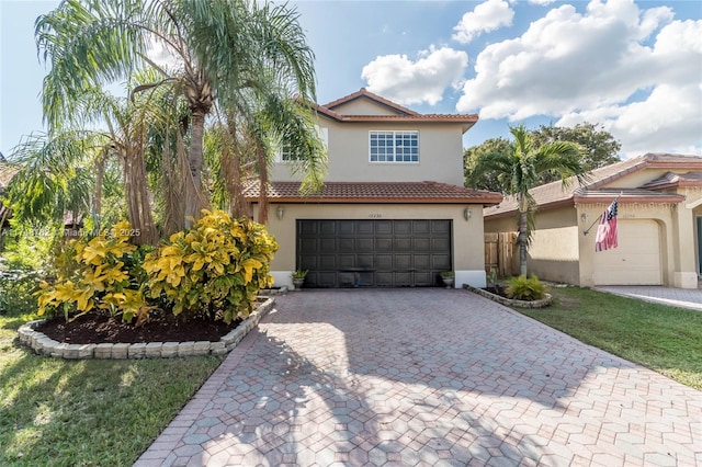 mediterranean / spanish home with a tile roof, decorative driveway, stucco siding, and an attached garage