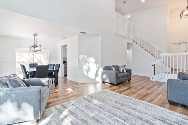 living area featuring baseboards, wood finished floors, an inviting chandelier, and stairway