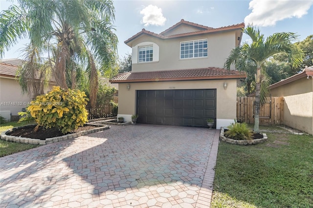 view of front of property with fence, a tiled roof, decorative driveway, an attached garage, and stucco siding
