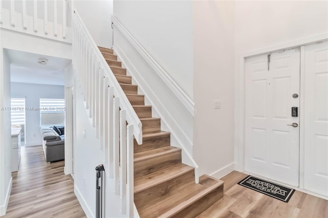 entrance foyer with baseboards, light wood-style floors, and stairs