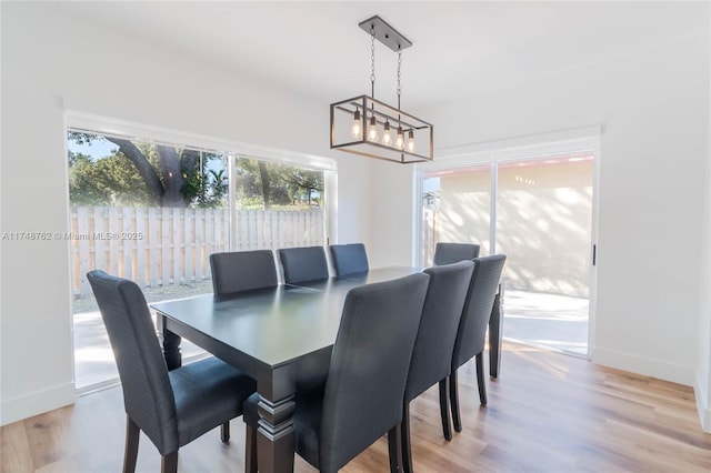 dining space with a chandelier, baseboards, and light wood finished floors