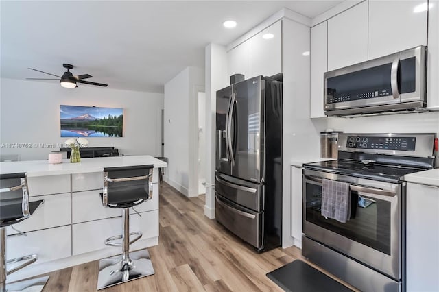 kitchen featuring light countertops, a ceiling fan, appliances with stainless steel finishes, light wood-type flooring, and white cabinets