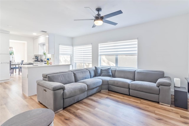 living area featuring light wood-style flooring, ceiling fan, and a wealth of natural light