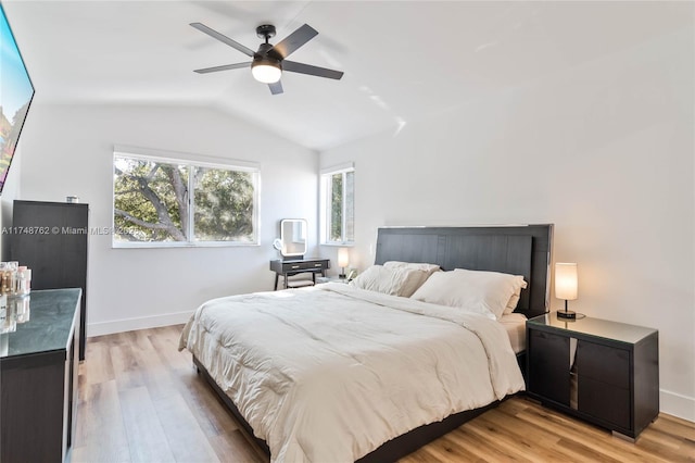 bedroom featuring baseboards, lofted ceiling, and light wood finished floors