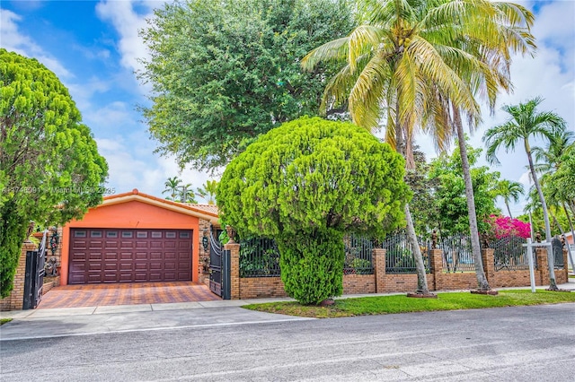 obstructed view of property featuring decorative driveway, fence, an attached garage, and stucco siding