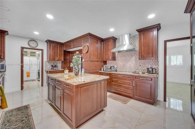 kitchen with decorative backsplash, wall chimney exhaust hood, a center island, marble finish floor, and recessed lighting