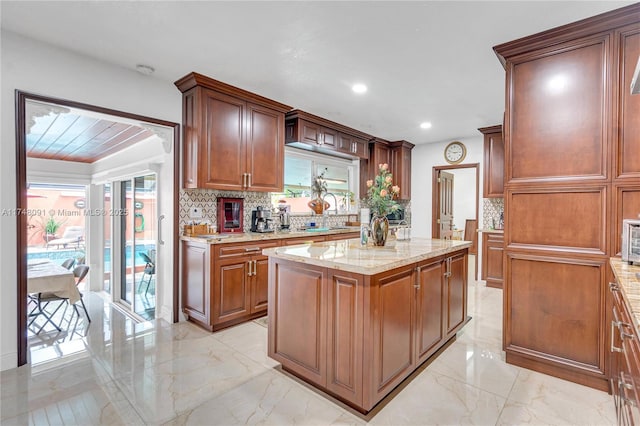 kitchen with marble finish floor, tasteful backsplash, a kitchen island, and a sink