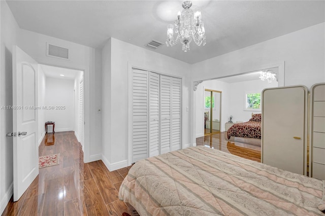 bedroom featuring a notable chandelier, a closet, visible vents, and wood finished floors