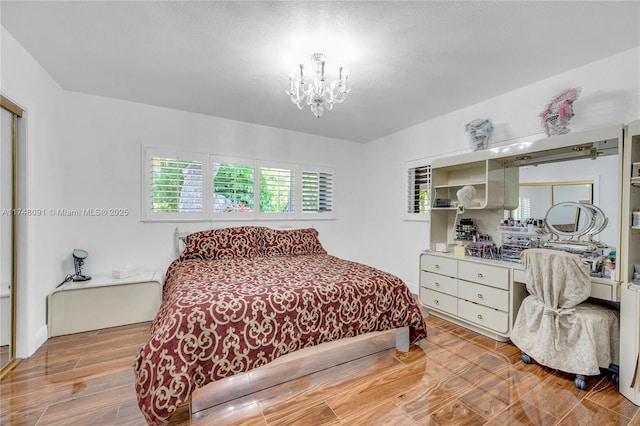 bedroom featuring light wood finished floors and a notable chandelier